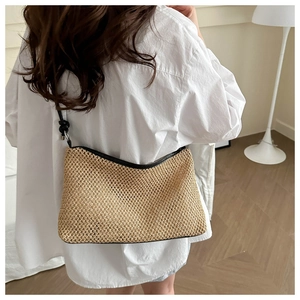 Model wearing a woven straw crossbody bag with black leather trim and strap for summer