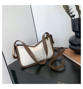 Detail van witte leren schoudertas met bruine bies en rich rabbit tekstbedrukking