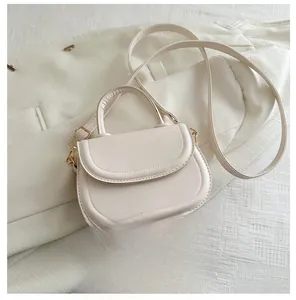 Detail view of cream mini saddle bag with golden hardware and PU leather texture