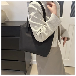 Minimalist black large capacity tote bag shown on model for daily commuting style