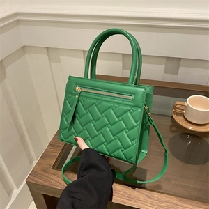 Green quilted handbag with diamond weave pattern and adjustable strap in lifestyle setting