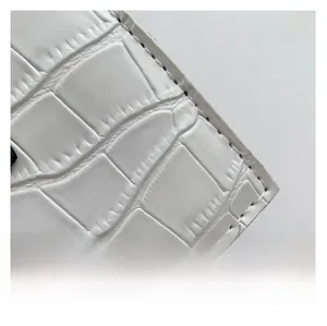 Close-up of white crocodile pattern leather texture and neat stitching on crossbody bag