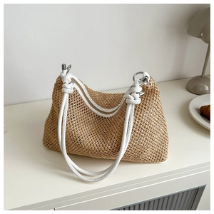 Close-up of the woven straw bag with white rope straps and silver metal hardware details