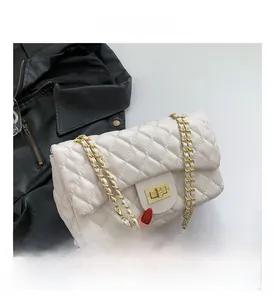 Detail view of white quilted crossbody bag featuring golden chain and twist lock clasp