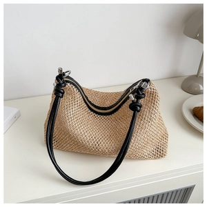 Detail of woven straw handbag with black leather knot strap and metal hardware
