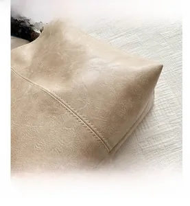 Close-up of beige PU leather tote with detailed double stitching and pebbled texture