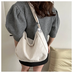 Macro shot of white corduroy shoulder bag with side pocket and cute dog charm pendant
