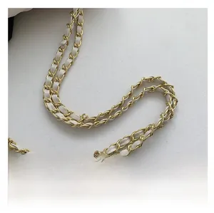 Detail showing high-quality gold metal chain interwoven with white leather strap