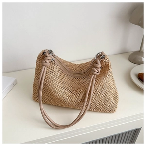 Close-up of beige woven shoulder bag featuring textured straw material and knotted strap detail