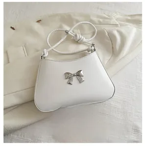 Detail view of the white crossbody bag showing size comparison with a smartphone