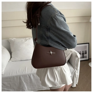 Detail of dark brown leather underarm bag with silver star ornament and knotted strap