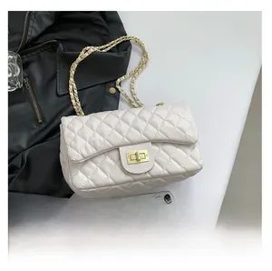 Macro view of white quilted faux leather bag with golden metallic clasp and chain strap