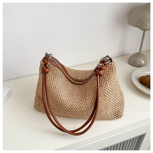 Detail of hand-woven beige straw bag with brown handle and knot strap for summer beach trips