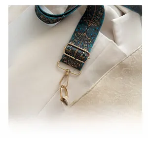 Detail of colorful geometric woven shoulder strap and golden metal hardware on white bucket bag
