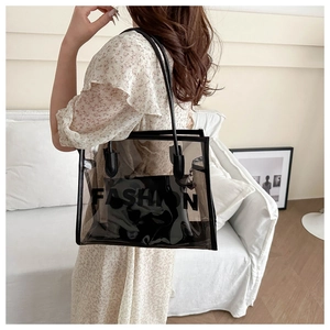 Detail view of transparent PVC tote bag with black handles and fashion lettering print