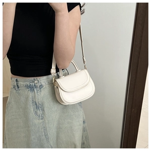 Detail of cream saddle bag featuring adjustable strap and smooth PU leather finish