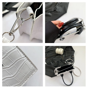 Detail of white crocodile embossed texture and black contrast handle on a small square bag