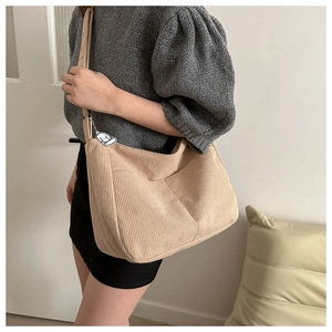 Detail of beige corduroy tote bag featuring a textured finish and cute dog charm accent