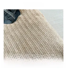 Primo piano della borsa tote in paglia beige con trama a spina di pesce e materiale morbido