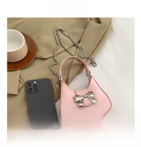 Detailed view of pink mini bow handbag with silver chain strap and smartphone for scale
