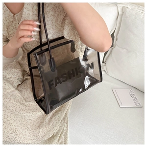 Close-up of transparent black PVC tote bag with FASHION logo and inner pouch