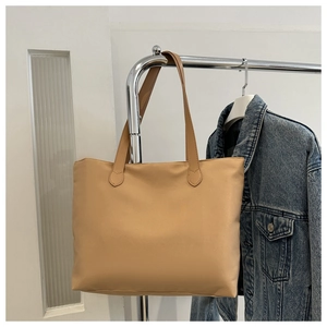 Detail of khaki tote bag hanging on a rack with denim jacket, showing nylon texture
