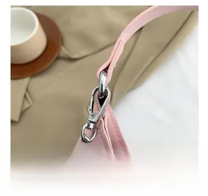 Close-up of silver metal buckle and chain hardware on a pink leather mini handbag