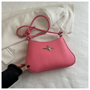 Detail of hot pink shoulder bag featuring a silver star emblem and knotted strap detail