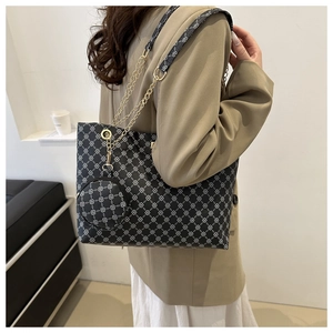 Detail of black printed tote bag with gold chain strap and mini hanging purse accessory