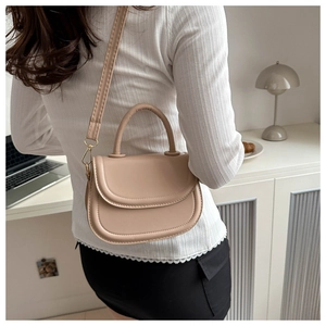 Detail of beige saddle bag with smooth leather finish and adjustable shoulder strap