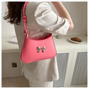 Detail of pink hobo bag featuring silver bow accent and knotted handle in a lifestyle setting