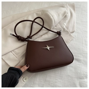 Detail of dark brown leather crescent bag with silver star hardware on a blazer