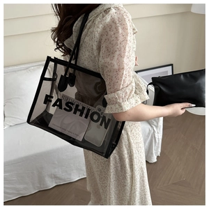 Detail of transparent PVC tote bag with black FASHION text and matching inner pouch