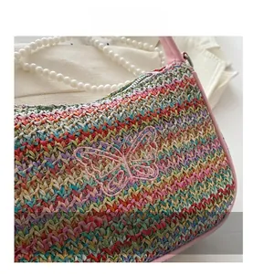 Détail de la texture en paille tressée colorée avec broderie papillon rose et perles