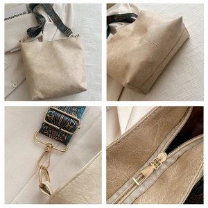 Detailed view of cream tote bag with vintage jacquard strap and gold hardware