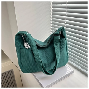 Detail of dark green corduroy tote bag with side pocket and cute sheep charm on book