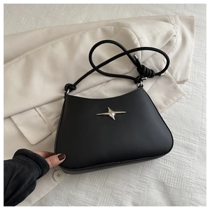 Detail of black leather underarm bag with silver star metal accent and thin straps
