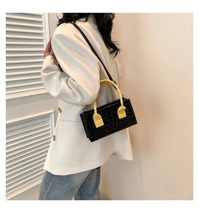 Detail of black faux crocodile skin handbag featuring contrasting bright yellow handle