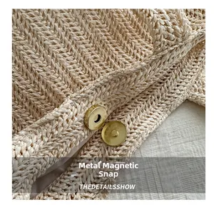 Dettaglio della chiusura magnetica dorata su borsa a tracolla intrecciata beige