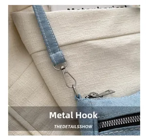 Detailed close-up of hardware hook and stitching on light blue denim shoulder bag