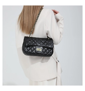 Detail of classic black quilted bag featuring gold metal twist lock and leather chain strap
