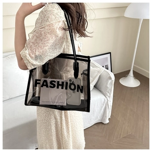 Detail shot of a large transparent tote bag with black trim and Fashion print