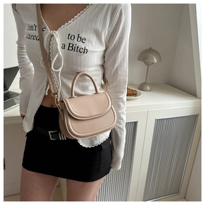 Detail of beige saddle bag showing smooth PU leather texture and gold metallic clasp
