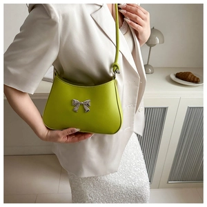 Close-up of grass green shoulder bag featuring a silver metal bow accent and smooth PU leather