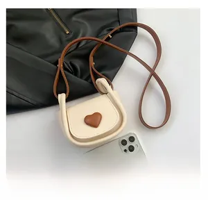 Size comparison showing mini saddle bag with heart detail next to a smartphone