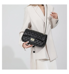 Detail of black quilted leather shoulder bag with gold twist lock and chain strap
