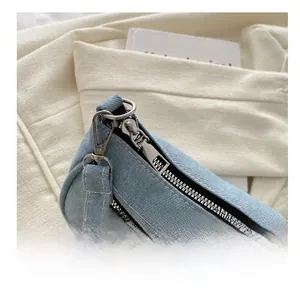 Close-up of smooth silver metal zipper and denim twill texture on the light blue bag