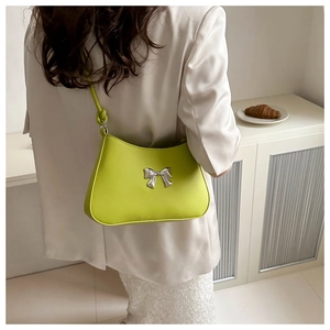 Detail of lime green baguette bag with silver bow accent and slim shoulder strap