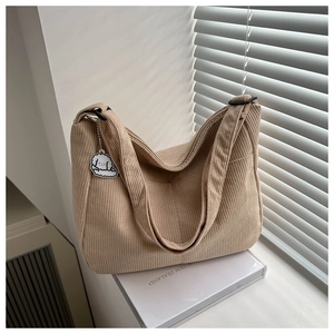 Detail of beige corduroy tote bag with cute dog pendant on a minimalist background