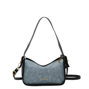 Graublaue Schultertasche mit schwarzem Lederbesatz und goldenem Logo auf weißem Grund